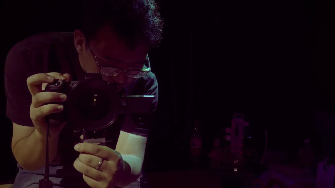 片头持相机者单帧，摄影者在暗场中显影